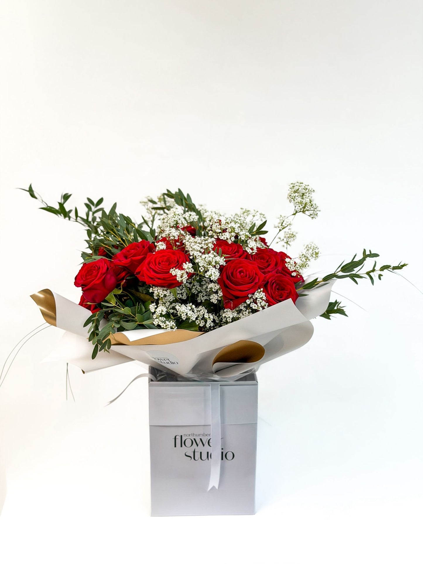 Bouquet of 24 red roses and white flowers in a box with 'Northumberland Flower Studio' branding on a white background