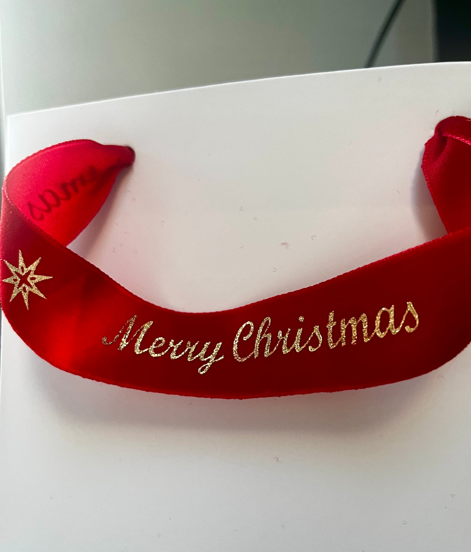 Red ribbon with 'Merry Christmas' text on a white gift bag 