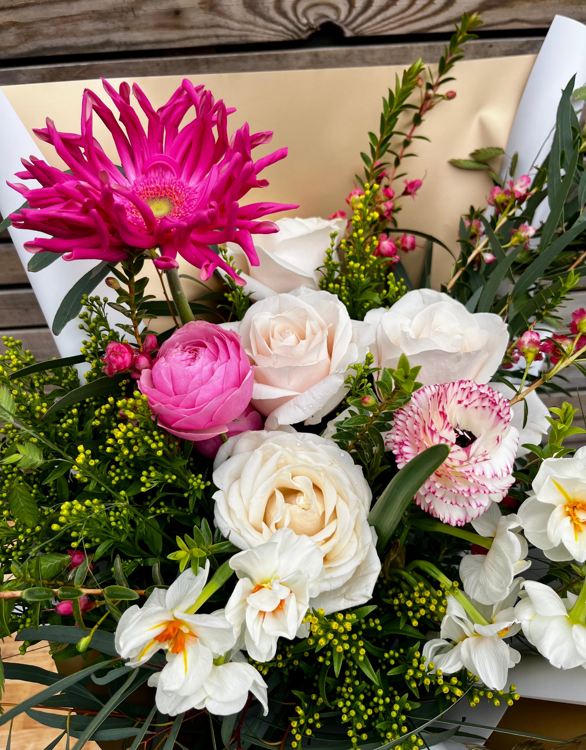 Bouquet of flowers with pink, white, and green colors on a wooden surface.