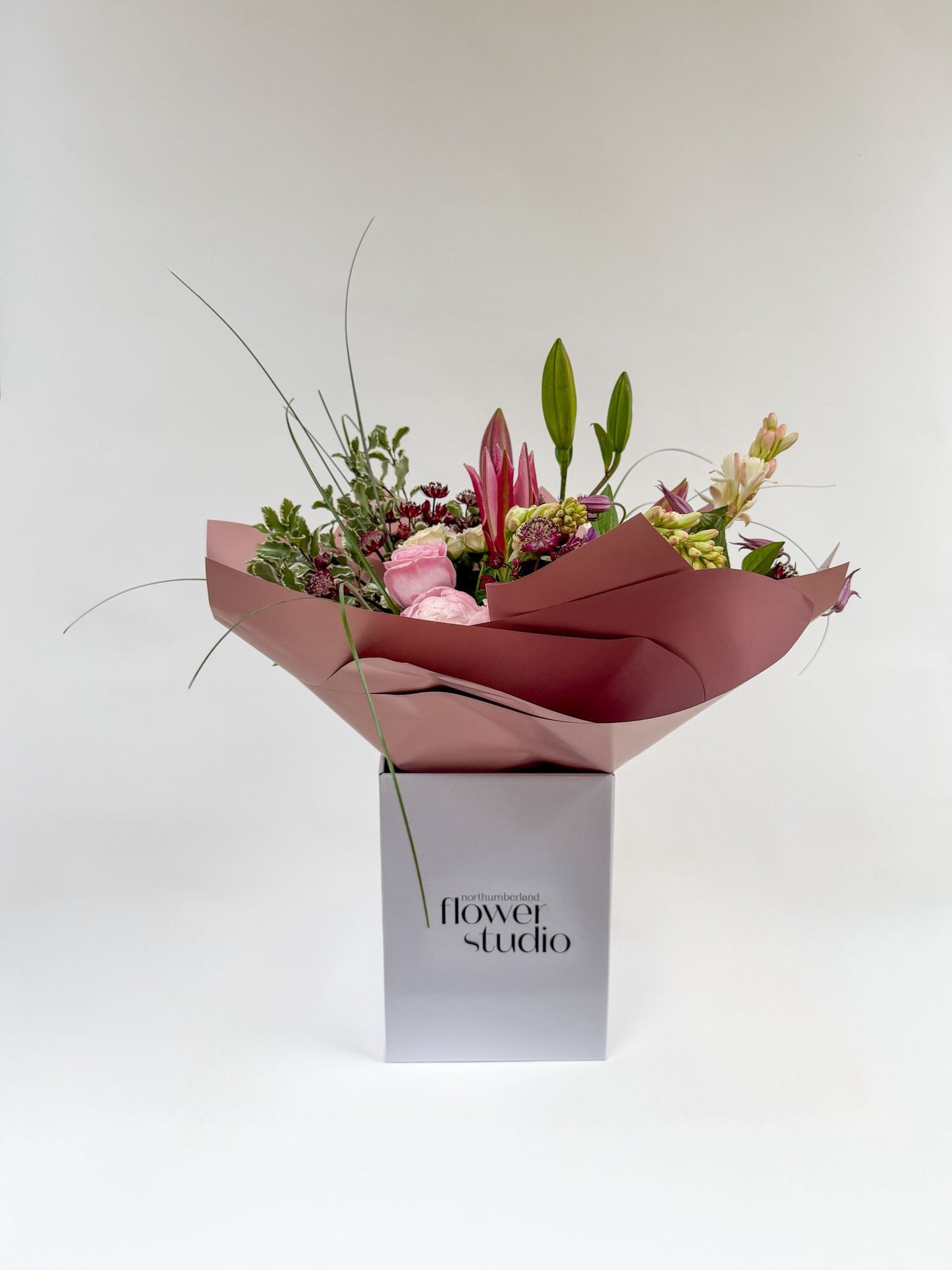 Bouquet of Mother’s Day flowers wrapped in pink paper with 'Northumberland Flower Studio' branding on a white background