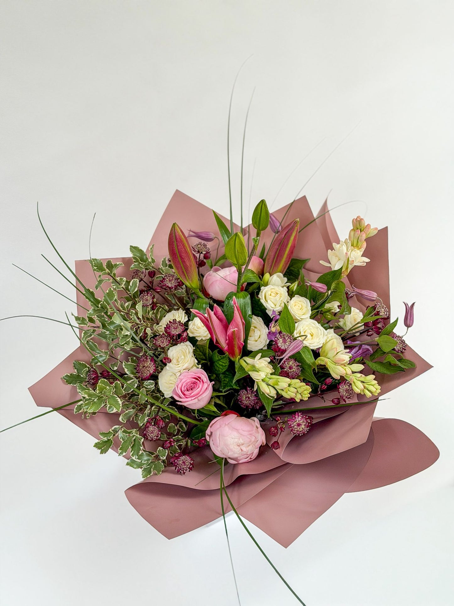 Bouquet of Mother’s Day flowers wrapped in pink paper on a white background