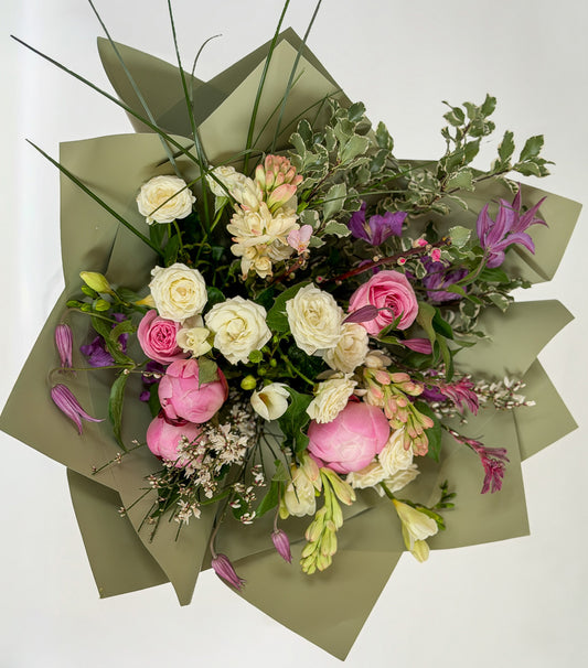 Bouquet of flowers with pink peonies, white spray roses, and purple flowers on a white background