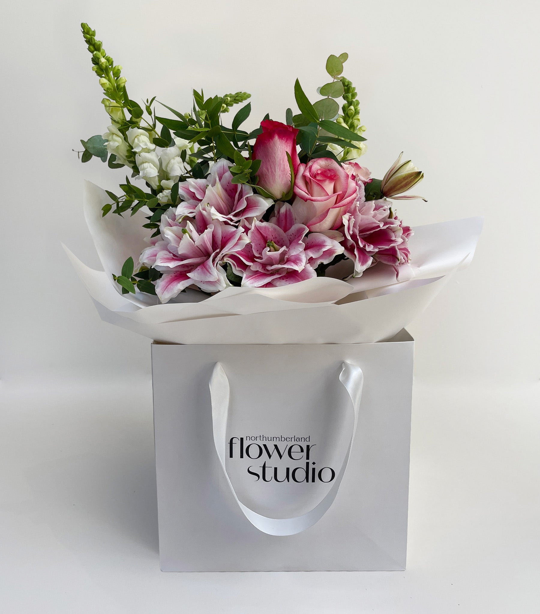 Bouquet of flowers in a white wrap with 'flower studio' branding on a white background