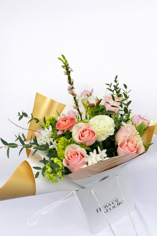 Bouquet of Mother’s Day flowers wrapped in gold paper with a white background