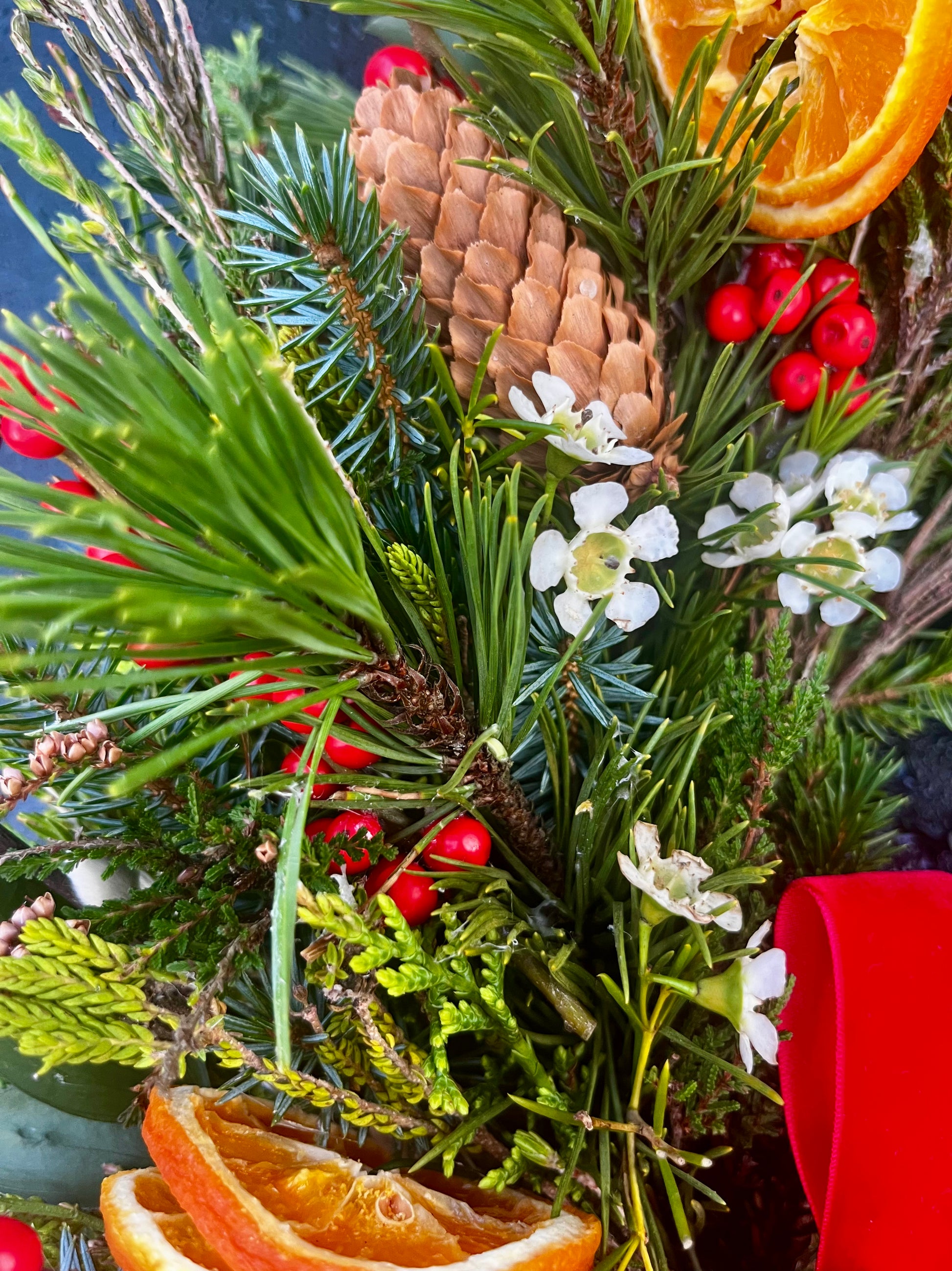 Decorative arrangement with pine cones, berries, and dried oranges on a blue background